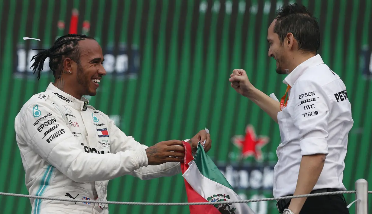 Pembalap Mercedes dari Inggris, Lewis Hamilton berselebrasi dengan anggota tim Marcelo Martinelli setelah berhasil menjuarai balapan GP Meksiko di Autodromo Hermanos Rodriguez, Mexico City (28/10/2019). (AP Photo/Rebecca Blackwell)