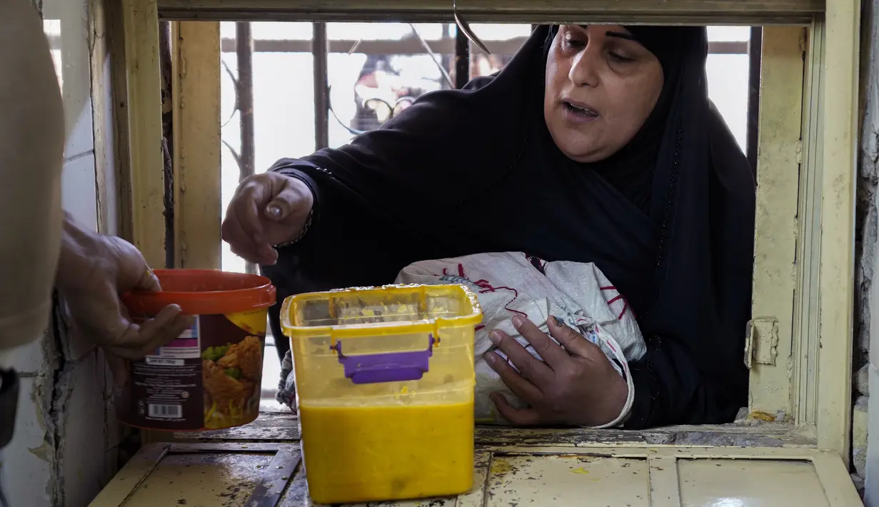 <p>Seorang wanita menerima makanan gratis yang dibagikan menjelang buka puasa saat bulan suci Ramadhan di Masjid Abdul Qadir al Gailani, Baghdad, Irak, Kamis (13/4/2023). (AP Photo/Hadi Mizban)</p>