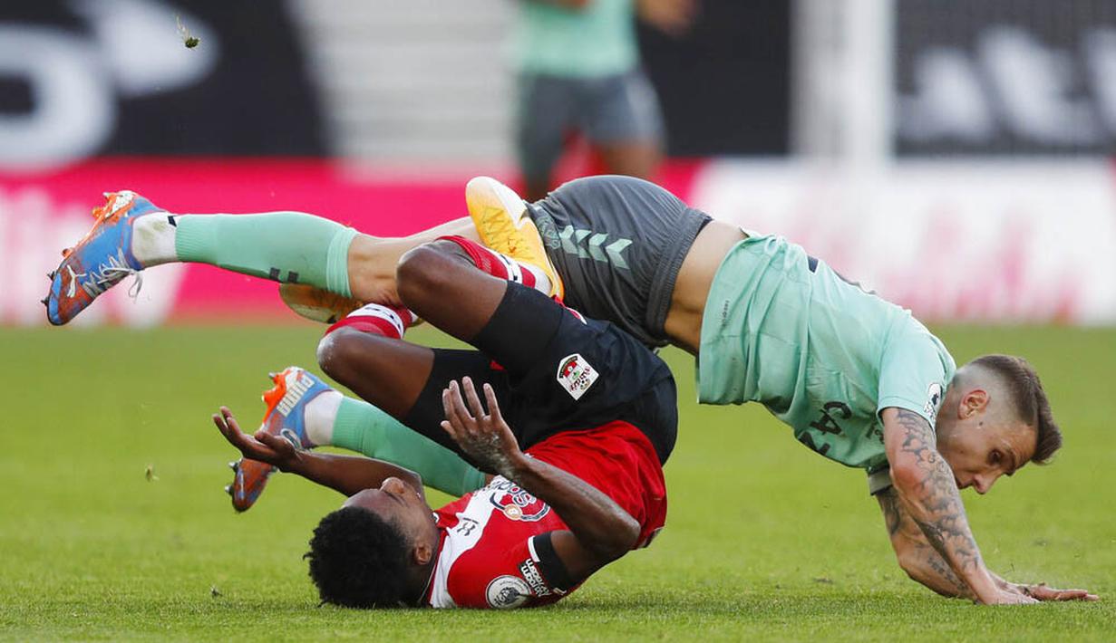 Pemain Everton, Lucas Digne, terjatuh saat berebut bola dengan pemain Southampton, Kyle Walker-Peters, pada laga Liga Inggris di Stadion St. Mary's Minggu (25/10/2020). Southampton menang dengan skor 2-0. (AP Photo/Frank Augstein, Pool)