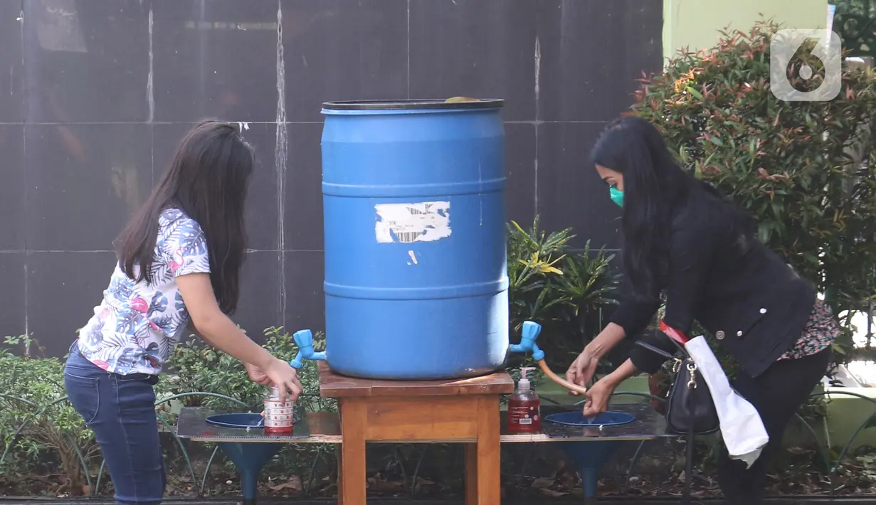 Wali murid dan siswa mencuci tangan sebelum pembagian laporan hasil belajar (rapor) kenaikan kelas di SD Negeri Menteng 01 Jakarta, Kamis (25/6/2020). Pembagian mengikuti protokol kesehatan COVID-19 serta membagikan rapor secara bertahap dari 24-26 Juni 2020. (Liputan6.com/Herman Zakharia)