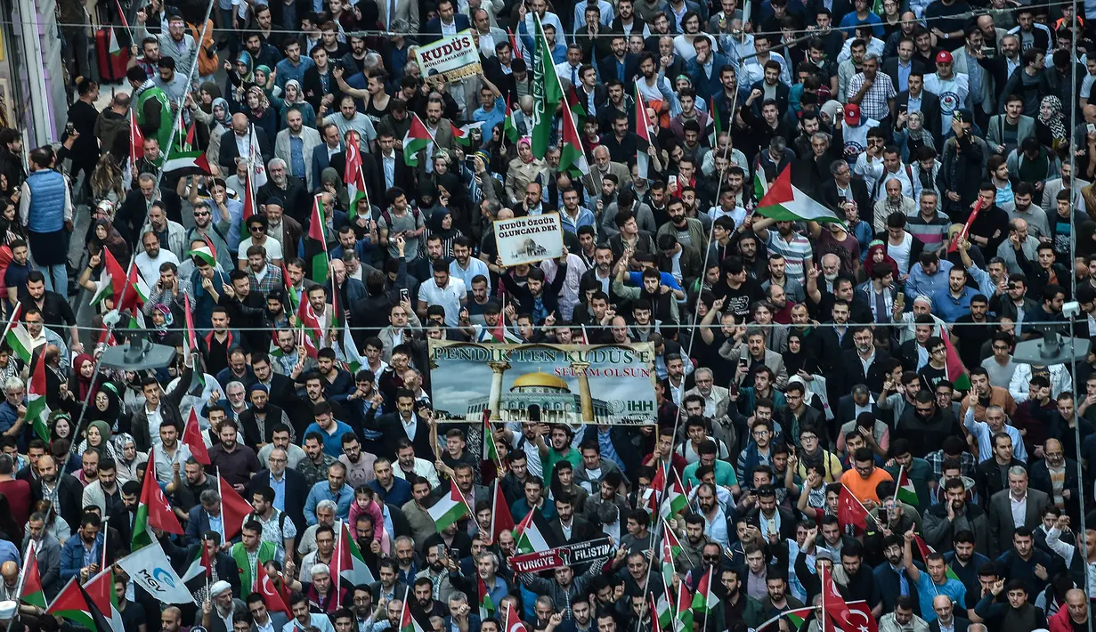 Para pengunjuk rasa membawa bendera Palestina saat menggelar aksi menolak perpindahan kedutaan AS dari Tel Aviv ke Yerusalem di Istikilal di Istanbul, Turki (14/5). (AFP/Ozan Kose)
