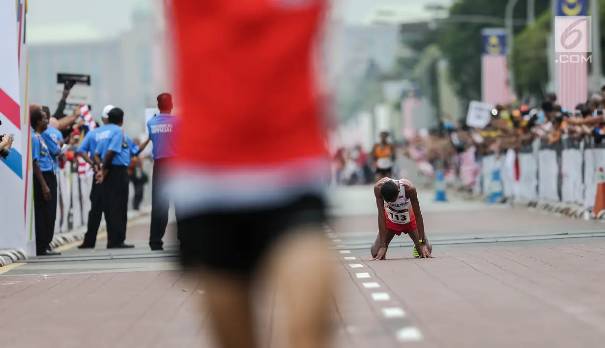 Pelari Indonesia Agus Prayogo saat melewati garis finis trek maraton SEA Games XXIX di Putra Jaya, Kuala Lumpur, Malaysia, Sabtu (19/8).  Posisi ketiga diisi pelari tuan rumah, Malaysia, Muhaizar Mohammad. (Liputan6.com/Faizal Fanani)