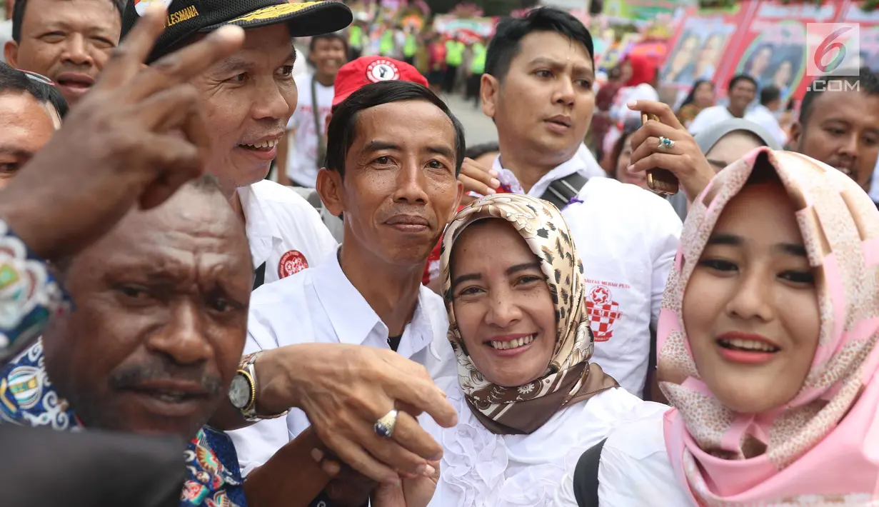 Seorang pria berwajah mirip Presiden Joko Widodo (Jokowi) berswafoto bersama warga yang memadati sekitar Gedung Graha Saba Buana, Solo, Rabu (8/11). Pria bernama David tersebut langsung jadi rebutan warga untuk berfoto bersama. (Liputan6.com/Angga Yuniar)