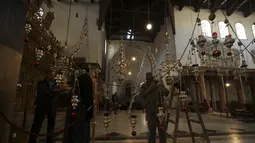 Seorang pekerja membersihkan perlengkapan penerangan menjelang Natal di kota Betlehem di Tepi Barat pada 22 Desember 2022. Menjelang perayaan Natal, Kota Bethlehem sudah bersolek. Dekorasi liburan dan cerita kelahiran Yesus menghiasi kota itu. (AFP/Hazem Bader)