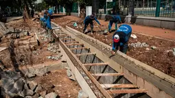 Sejumlah pekerja menyelesaikan pembuatan saluran air di Jalan Asia Afrika, Senayan, Jakarta, Rabu (5/4). Pembuatan saluran air tersebut untuk menanggulangi genangan air saat hujan turun. (Liputan6.com/Gempur M Surya)