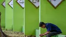 <p>Seorang pria berdoa saat memperingati 18 tahun musibah gempa dan tsunami di kuburan massal Siron, Aceh, Senin (26/12/2022). Sejumlah warga mendatangi Kuburan Massal Siron untuk memenjatkan doa saat peringatan 18 tahun musibah gempa dan tsunami Aceh 2004. (AFP/Chaideer Mahyuddin)</p>