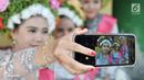 Sejumlah gadis berswafoto saat menunggu upacara adat Ngarot dimulai di Desa Lelea, Indramayu, Jawa Barat, Rabu (19/12). Hari Rabu minggu ketiga di bulan Desember dipercaya oleh masyarakat setempat sebagai hari keramat. (Merdeka.com/Iqbal Nugroho)