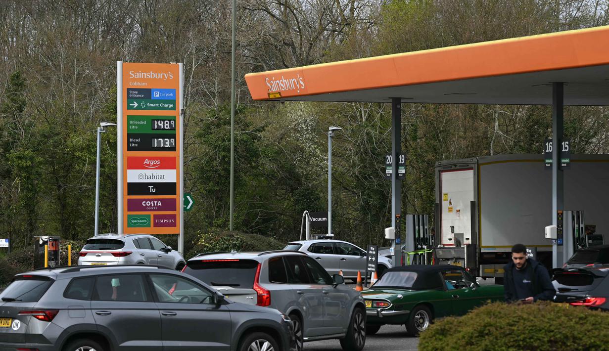 Situasi ini juga memicu kelangkaan serta kenaikan harga Bahan Bakar Minyak (BBM) di berbagai negara, salah satunya Inggris, yang mengalami kenaikan sekitar 15 persen dibandingkan sebelum konflik. Tampak dalam foto, para pengemudi mengantre di sebuah Stasiun Pengisian Bahan Bakar Umum (SPBU) di Cobham, barat daya London pada 29 Maret 2026. (JUSTIN TALLIS/AFP)