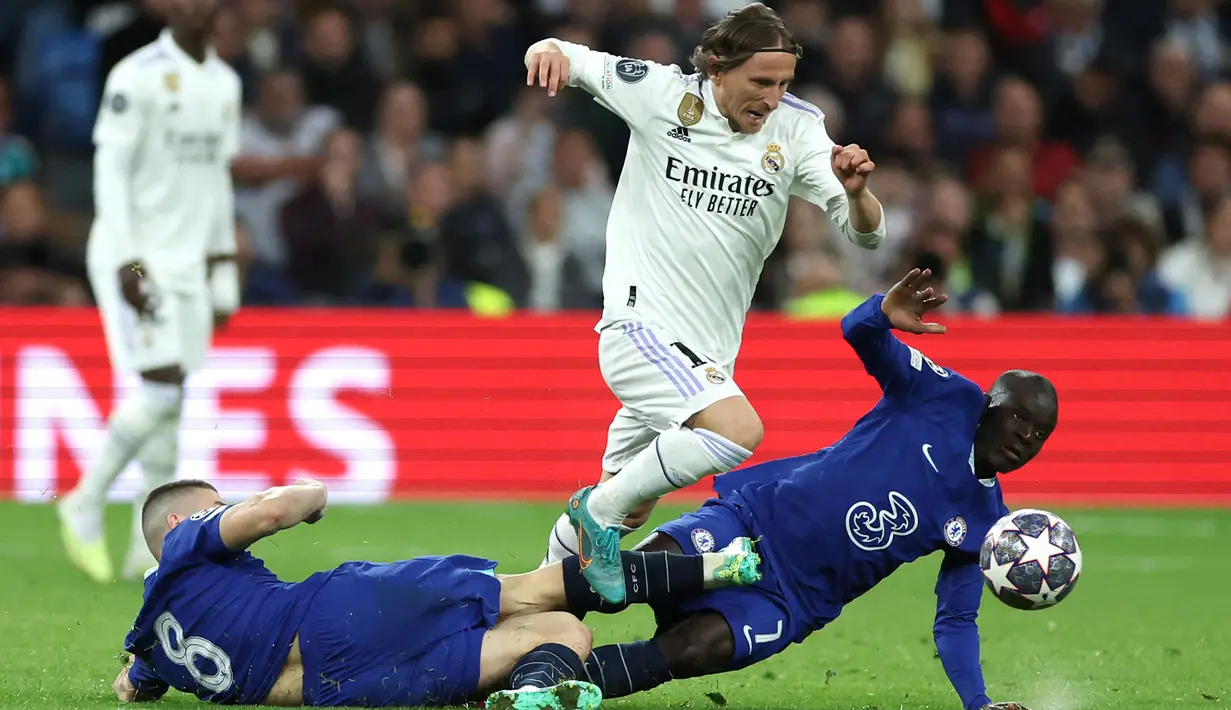 Pemain Real Madrid, Luka Modric berusaha melewati pemain Chelsea, Mateo Kovacic (kiri) dan N'Golo Kante pada laga leg pertama Liga Champions 2022/2023 di Santiago Bernabeu, Madrid, Kamis (13/04/2023) WIB. Los Blancos menang dengan skor 2-0. (AFP/Pierre-Philippe Marcou)