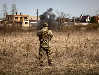 Seorang anggota regu penjinak bom melihat asap di ladang ranjau dekat Brovary, timur laut Kiev, di tengah invasi militer Rusia pada 14 April 202. Rusia sudah menarik tentara mereka dari Kiev dan mengalihkan sebagian besar fokus perangnya ke wilayah Ukraina timur pada akhir Maret. (FADEL SENNA/AFP)