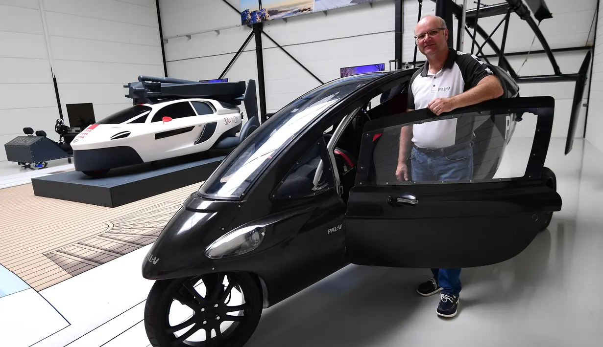 Chief Marketing Officer, Markus Hess berfoto bersama mobil terbang PAL-V di Raamsdonksveer, Belanda (30/5). Kendaraan dua tempat duduk ini mengkonversi dari motor roda tiga menjadi girokopter dalam 10 menit. (AFP Photo/Emmanuel Dunand)
