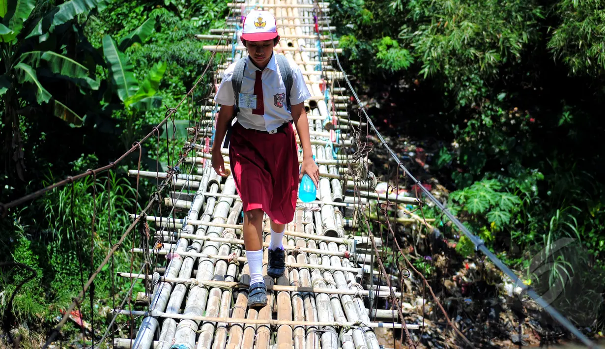 Para siswa SD ini terbiasa melewati jembatan gantung di atas kali Ciliwung untuk menuju ke sekolah, Jakarta, Selasa (17/3/2015). Padahal jembatan tersebut sangat membahayakan dan berisiko (Liputan6.com/Yoppy Renato)