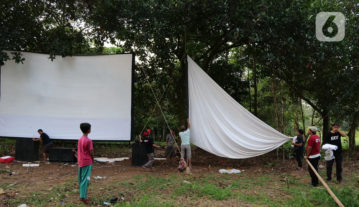 Teknisi menyiapkan layar tancap sebelum pertunjukkan di kawasan Sawangan, Depok, Jawa Barat, Sabtu (11/7/2020). Layar tancap atau bioskop terbuka menjadi alternatif bagi warga untuk menikmati film di tengah penerapan new normal di kawasan Jabodetabek. (Liputan6.com/Herman Zakharia)