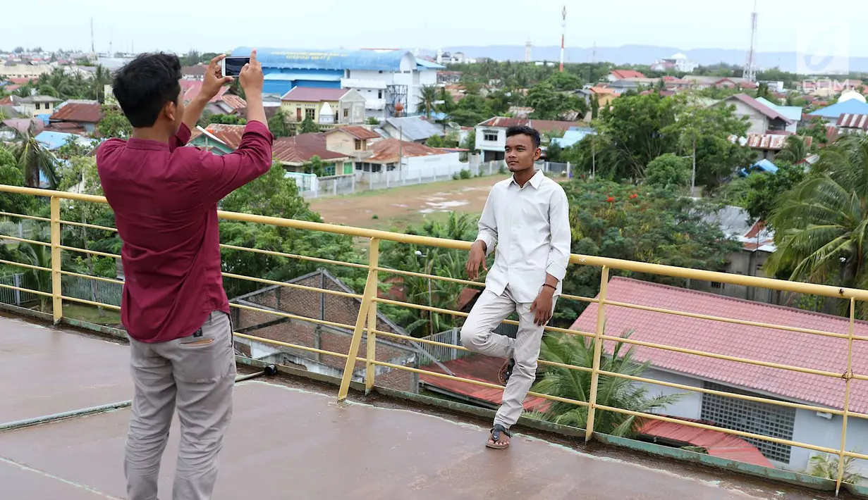 Pengunjung foto di Monumen Kapal Pembangkit Listrik Tenaga Diesel (PLTD) Apung 1 di Aceh, Selasa (31/7). Monumen peringatan dibangun untuk mengenang korban jiwa yang jatuh akibat tsunami Aceh. (Liputan6.com/Immanuel Antonius)