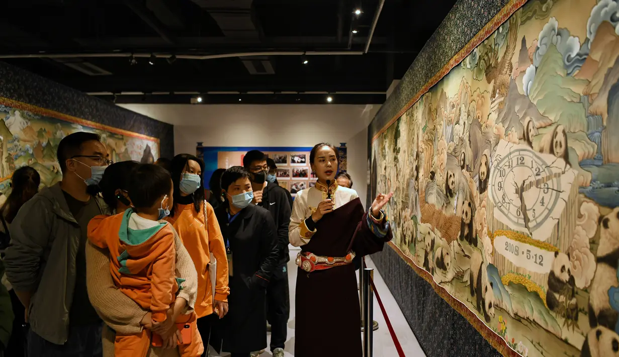 Pemandu menjelaskan lukisan thangka bertema panda kepada pengunjung di Perpustakaan Provinsi Sichuan, Chengdu, Provinsi Sichuan, China, 11 Oktober 2020. Thangka adalah semacam lukisan di atas sutra bersulam dan biasanya menggambarkan makhluk suci Buddhis, peristiwa, atau mandala. (Xinhua/Wang Xi)