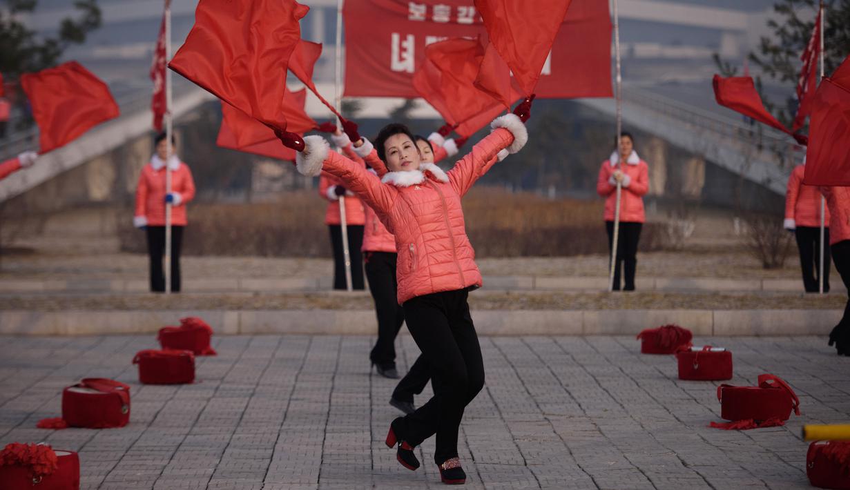 Kelompok Serikat Wanita Sosialis mengibarkan bendera saat melakukan propaganda di depan Hotel Ryugyong, Pyongyang, Korea Utara, Sabtu (9/3). Kehadiran mereka dimaksudkan untuk memotivasi para pekerja agar lebih semangat. (Ed Jones/AFP)