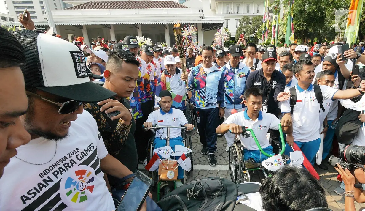 Gubernur DKI, Anies Baswedan membawa obor saat Pawai Obor Asian Para Games di Balai Kota DKI Jakarta, Minggu (30/9). Pawai obor dimulai dari Balai Kota dan berakhir di Gedung Kementerian Pemuda dan Olahraga (Kemenpora). (Liputan6.com/Herman Zakahria)