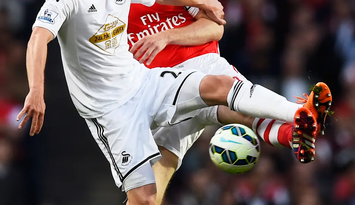 Bek Arsenal, Per Mertesacker(kanan) berebut bola dengan bek Swansea City Gelandang Swansea City Gylfi Sigurdsson saat Laga Liga Premier Inggris di Emirates Stadium, Selasa (12/5/2015). Swansea City menang 1-0 atas Arsenal. (Reuters/ADylan Martinez)