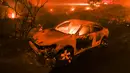 Sebuah kendaraan terbakar saat kebakaran melanda Pacific Coast Highway di Malibu, California, AS, Jumat (9/11). Calabasas dan Malibu merupakan permukiman bagi sejumlah selebriti papan atas AS. (AP Photo/Ringo H.W. Chiu)