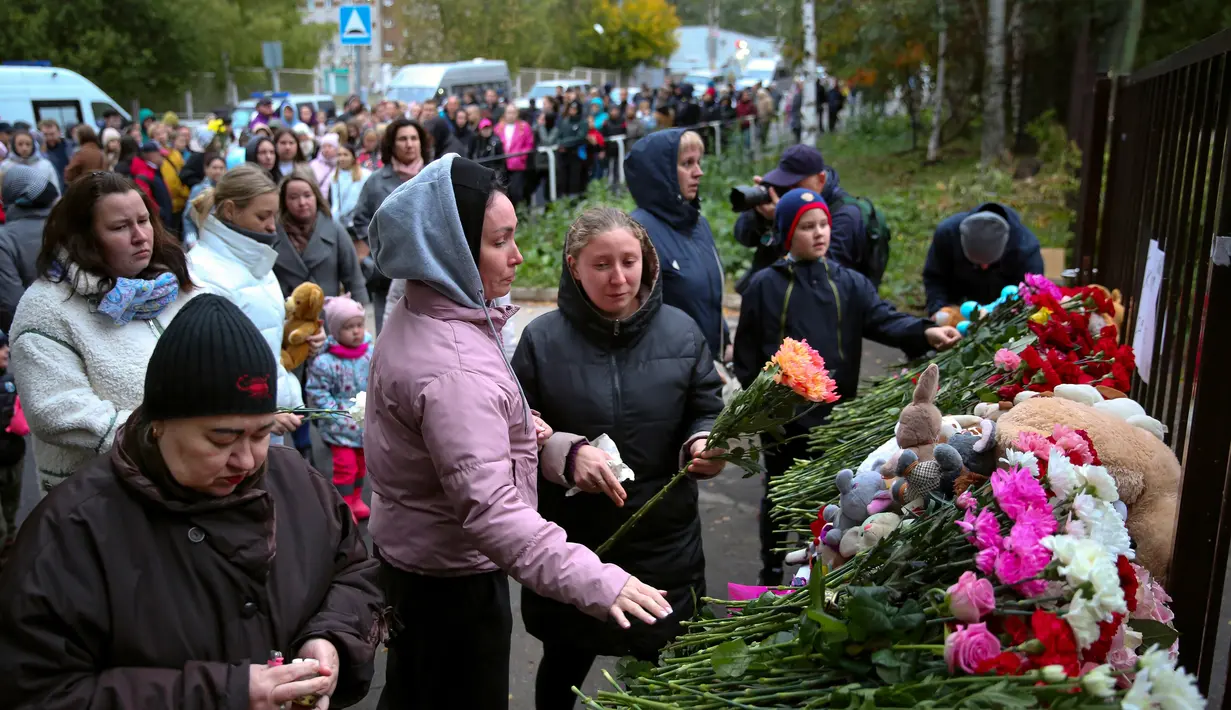 <p>Orang-orang berkumpul untuk meletakkan bunga, mainan, dan menyalakan lilin untuk mengenang para korban penembakan di Sekolah No. 88, Izhevsk, Rusia, Senin (26/9/2022). Sebanyak 982 siswa dan 80 guru dari sekolah itu saat ini telah dievakuasi. (AP Photo/Sergei Kuznetsov)</p>