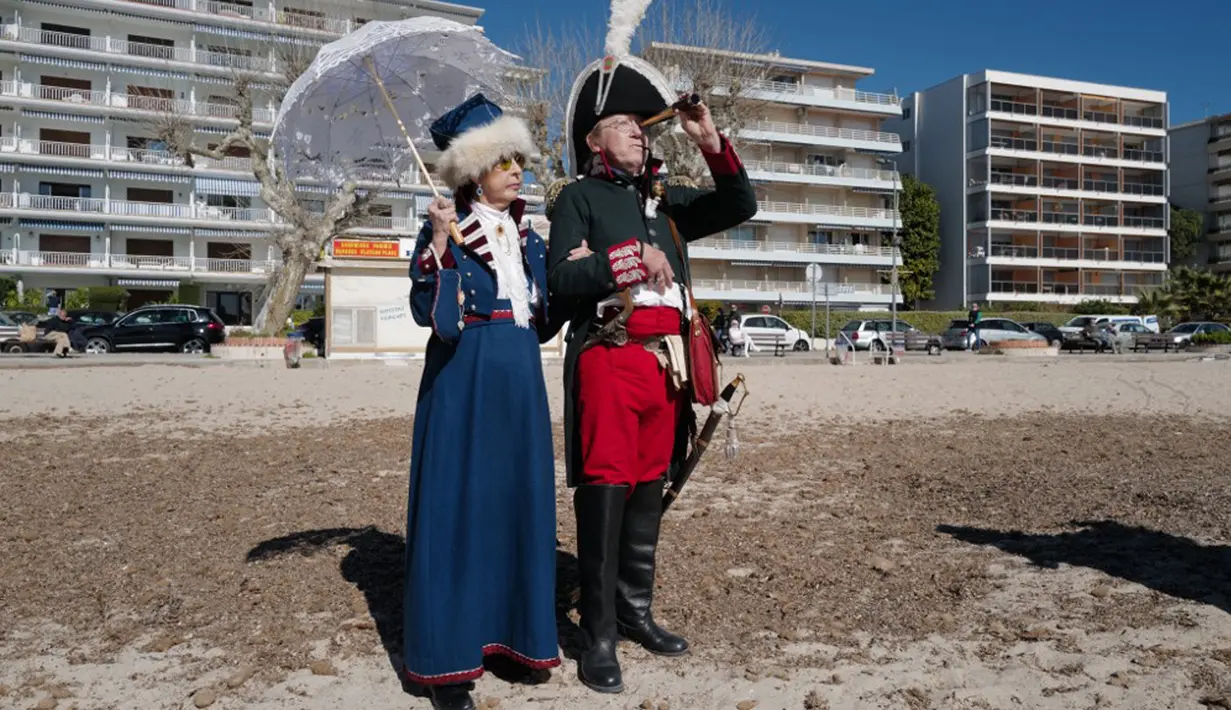Orang-orang yang mengenakan kostum era Napoleon Bonaparte berdiri di pantai dalam rangka peringatan 200 tahun kematian Napoleon Bonaparte di Saint-Helene, Golfe-Juan, Prancis, 16 Maret 2021. Napoleon berasal dari sebuah keluarga bangsawan lokal dengan nama Napoleone di Buonaparte. (Valery HACHE/AFP)