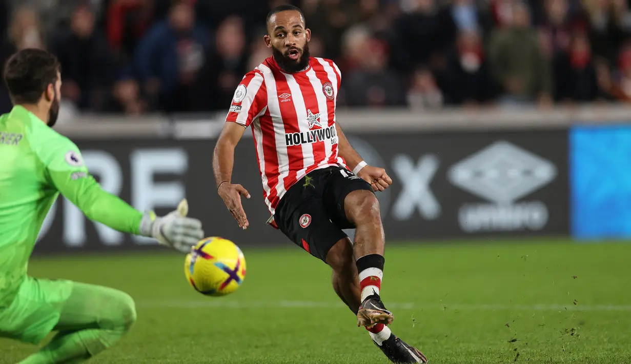 Striker Brentford, Bryan Mbeumo mencetak gol ke gawang Liverpool yang dijaga Alisson Becker pada laga Liga Inggris 2022/2023 di Gtech Community Stadium, London (2/1/2023). Bryan Mbeumo tampil di Liga Inggris bersama Brentford yang telah diperkuatnya sejak awal musim 2019/2020. Ia ikut membawa Brentford promosi ke Premier League pada awal musim 2021/2022. Hingga kini ia telah tampil dalam 73 laga di Premier League dengan torehan 13 gol dan 15 assist. (AFP/Adrian Dennis)