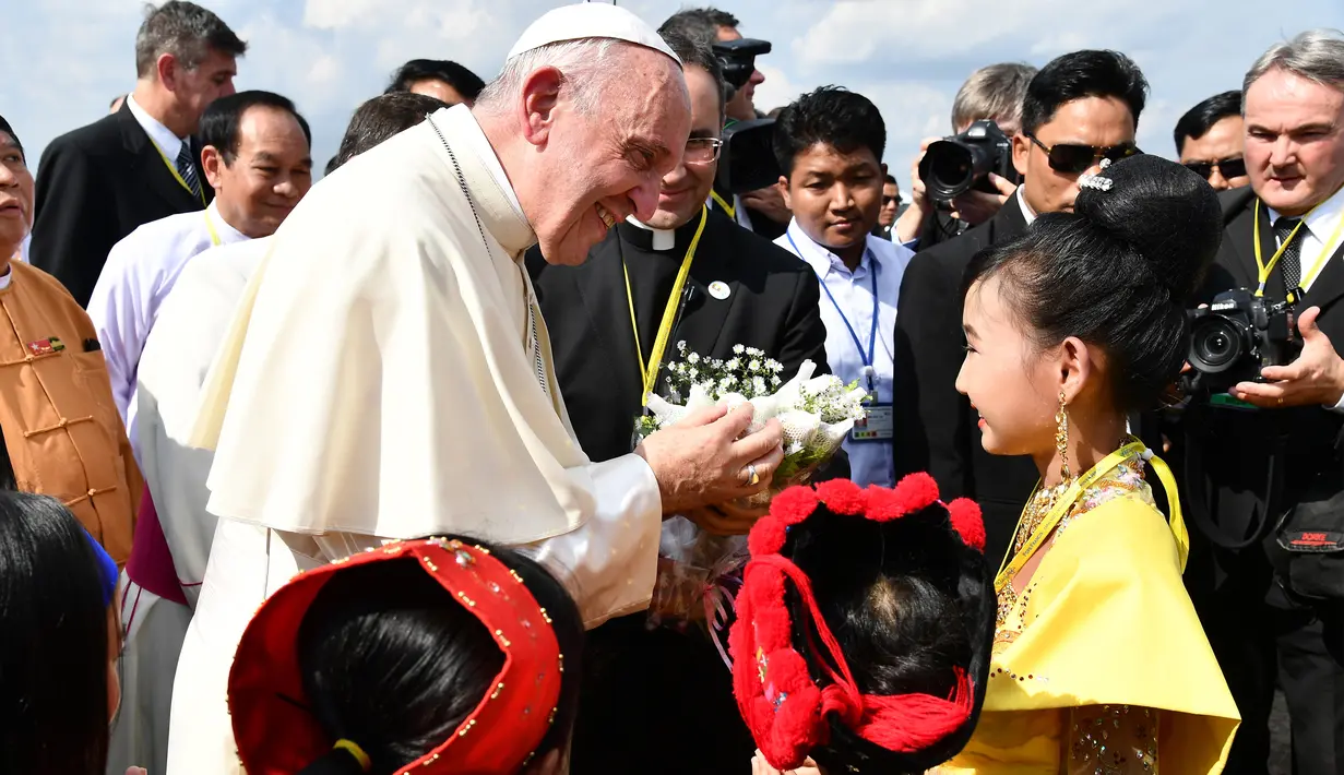 Paus Fransiskus menerima bunga saat disambut anak-anak di Bandara Internasional Yangon, Myanmar (27/11). Kedatangan Paus juga disambut dengan pakaian tradisional etnik, lambaian bendera dan tari-tarian di bandara Yangon. (AFP Photo/Vincenzo Pinto)