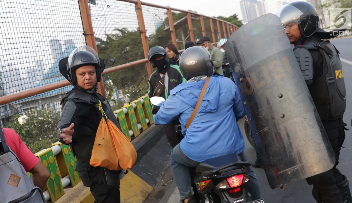 Personel Brimob mengatur arus lalu lintas yang tersendat akibat sejumlah pengendara dan warga berhenti menyaksikan aksi unjuk rasa yang dilakukan mahasiswa dari berbagai perguruan tinggi di sekitar Jembatan Layang Gerbang Pemuda, Jakarta, Selasa (1/10/2019). (Liputan6.com/Helmi Fithriansyah)