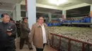 Gambar tak bertanggal yang dirilis pada 19 November 2019, pemimpin Korea Utara Kim Jong-un (kanan) mengunjungi pabrik pengolahan ikan di lokasi yang dirahasiakan di Korea Utara. Kim Jong-un berbicara dengan para pekerja dan sesekali tertawa saat berkeliling pabrik.  STRINGER/KCNA VIA KNS/AFP)