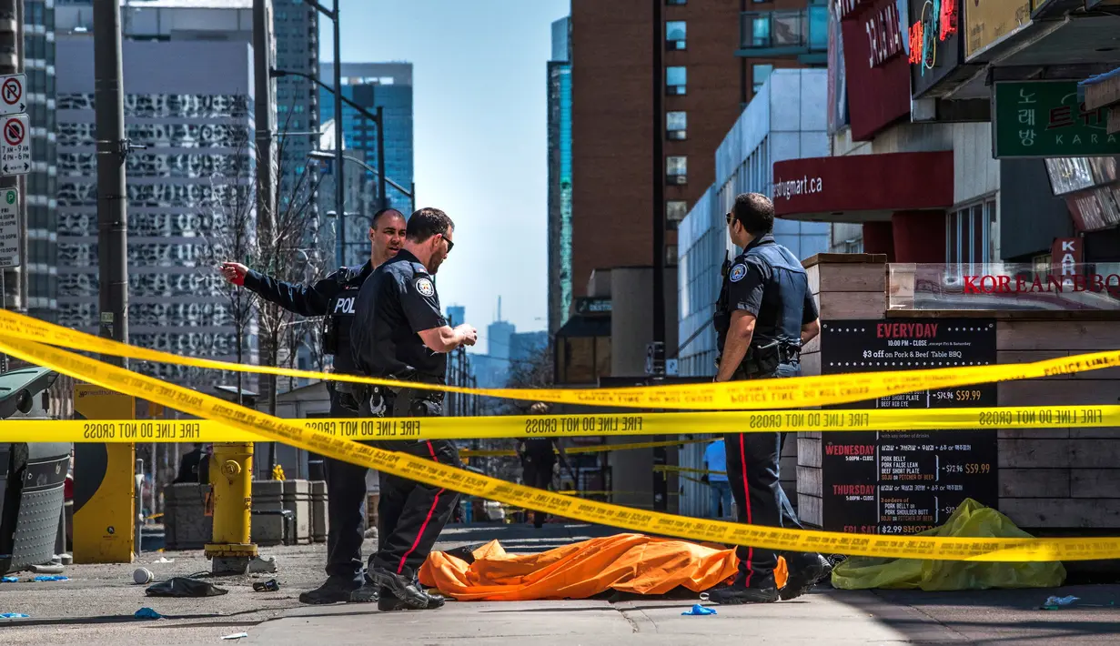 Petugas polisi berdiri dekat salah satu jasad akibat serangan mobil di Toronto bagian utara, Kanada, Senin (23/4). Serangan terjadi ketika sebuah van bergerak ke arah pejalan kaki di jalanan sibuk Toronto. (Aaron Vincent Elkaim/The Canadian Press via AP)