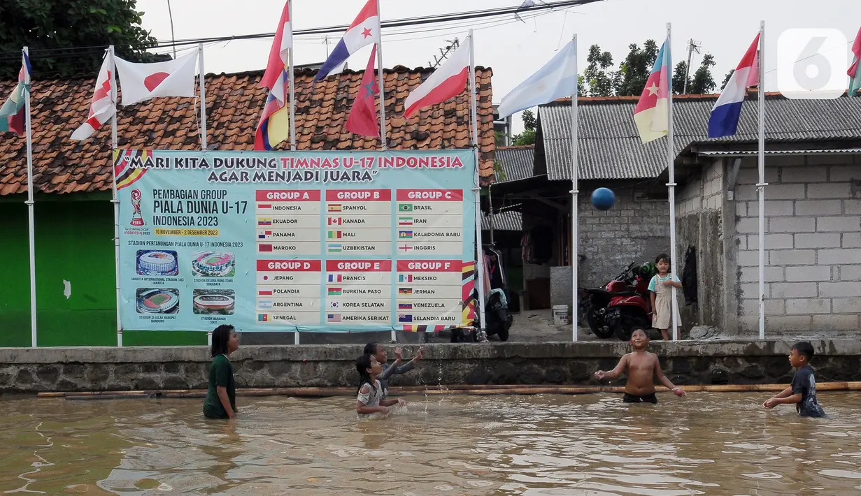 Anak-anak bermain bola dengan barisan tiang bendera negara peserta Piala Dunia U-17 2023 yang mana Indonesia sebagai tuan rumah di Kampung Asem, Kelurahan Marga Mulya, Kecamatan Bekasi Utara, Bekasi, Jawa Barat, Kamis (16/11/2023). Sebelumya, tiang-tiang tersebut diperuntukkan untuk bendera partai-partai menyambut pemilu dalam pesta demokrasi. (merdeka.com/Imam Buhori)