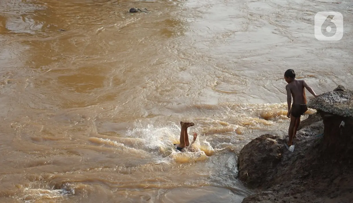 Anak-anak berenang di bantaran Sungai Ciliwung, Jakarta, Senin (5/10/2020). Derasnya aliran Sungai Ciliwung akibat hujan deras yang mengguyur Jakarta tidak menyurutkan kemauan anak-anak tersebut untuk tetap berenang, meski dapat membahayakan keselamatan mereka. (Liputan6.com/Immanuel Antonius)