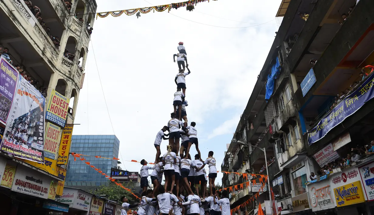 Pemuda India membentuk piramida manusia dalam perayaan Festival Janmashtami di Mumbai, Senin (3/9). Piramida manusia itu untuk memecahkan pot berisikan susu yang menggantung di langit-langit rumah supaya bisa diambil isinya. (INDRANIL MUKHERJEE/AFP)