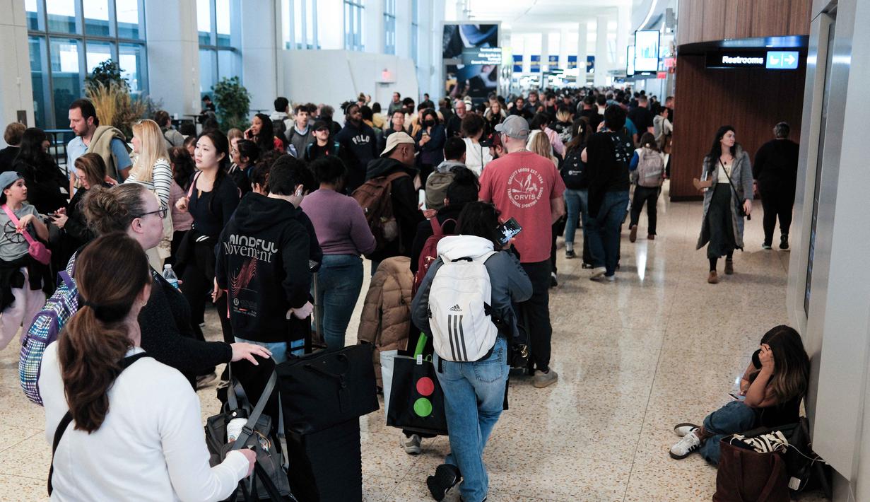 Akibatnya, ribuan petugas Administrasi Keamanan Transportasi (TSA) terpaksa bekerja tanpa gaji, memicu lonjakan absensi dan pengunduran diri massal. Tampak dalam foto, antrean para penumpang untuk melewati pemeriksaan keamanan di Bandara LaGuardia, New York pada Minggu 22 Maret 2026. (CHARLY TRIBALLEAU/AFP)