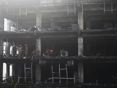 Anggota Pasukan Tanggap Bencana Nasional dan petugas pemadam kebakaran memeriksa sebuah gedung komersial sehari setelah kebakaran terjadi di New Delhi, India, Sabtu (14/5/2022). Kebakaran yang melanda gedung perkantoran empat lantai di Delhi, pada Jumat 13 Mei 2022, menewaskan sedikitnya 27 orang dan melukai sedikitnya 12 orang, kata layanan darurat. (Sajjad HUSSAIN / AFP)
