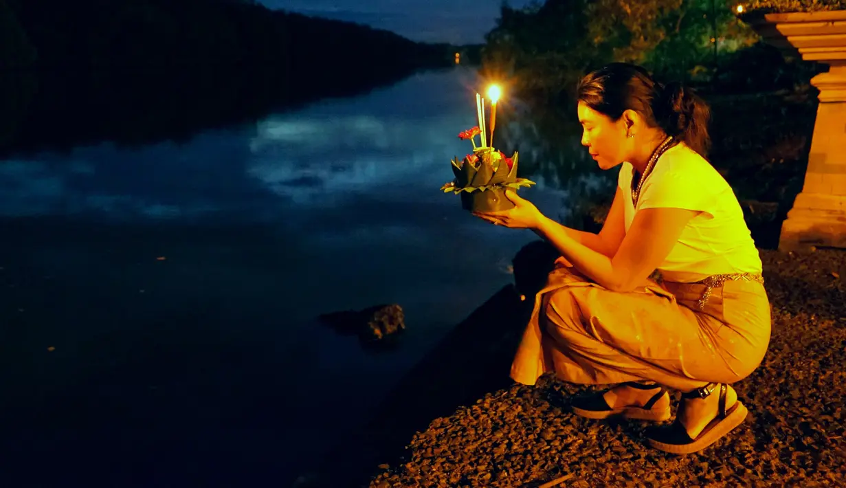 Seorang wanita bersiap menghanyutkan lentera air dalam Festival Loy Krathong di Bandar Seri Begawan, Brunei (31/10/2020).  Sekitar 250 orang termasuk sejumlah warga Thailand yang tinggal di Brunei menghanyutkan lentera air untuk perdamaian dan keberuntungan. (Xinhua/Jeffrey Wong)