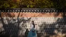 Seorang wanita mengenakan pakaian tradisional hanbok berpose saat difoto di bawah pohon ginkgo di istana Gyeongbokgung di Seoul (31/10). Pohon ini dikenali mirip dengan fosil 270 juta tahun lalu. (AFP Photo/Ed Jones)