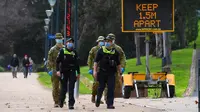 Petugas kepolisian dan tentara berpatroli di jalur lari yang populer di Melbourne, Selasa (4/8/2020). Negara bagian Victoria di Australia, khususnya ibu kota Melbourne mengumumkan status darurat bencana COVID-19 pada Minggu (2/8) waktu setempat. (William WEST / AFP)