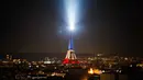 Foto ini menunjukkan Menara Eiffel yang diterangi dengan warna bendera nasional Prancis saat peringatan ke-10 serangan teroris Paris yang terjadi pada 2015, di Paris, pada 12 November 2025. Prancis memperingati satu dekade tragedi berdarah pada 13 November 2015. (Dimitar DILKOFF/AFP)