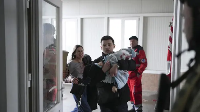 <p>Marina Yatsko tampak berlari ketika putranya yang masih bayi digendong ke rumah sakit oleh kekasihnya pada Maret 2022. Bayi itu adalah korban serangan Rusia di Mariupol, Ukraina. (AP Photo/Evgeniy Maloletka, File)</p>