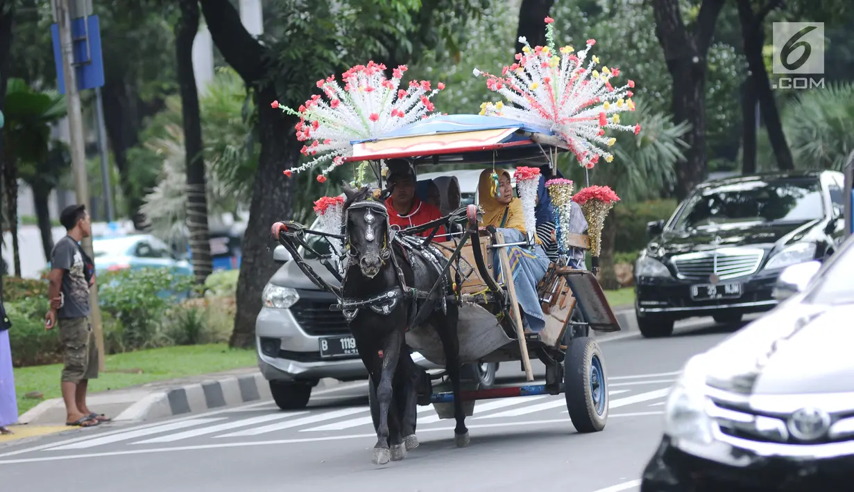 Delman hias membawa penumpang melintasi Jalan Medan Merdeka Selatan di luar kawasan Monas, Jakarta, Selasa (26/12). Pemprov DKI Jakarta menguji coba kembali beroperasinya delman hias di luar kawasan Monas, Jakarta. (Liputan6.com/Helmi Fithriansyah)