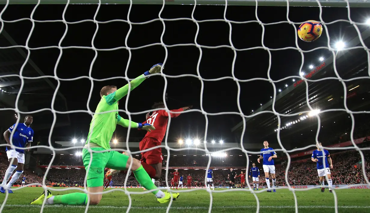 Penyerang Liverpool Divock Origi saat memasukan bola ke gawang kiper Everton, Jordan Pickford selama pertandingan Liga Inggris di Anfield Stadium (2/12). Liverpool menang tipis 1-0 atas Everton. (AP Photo / Jon Super)