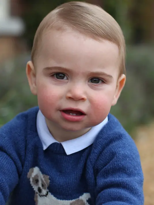 Foto yang dirilis oleh Kensington Palace pada 22 April 2019 memperlihatkan Pangeran Louis di rumahnya di Norfolk, Anmer Hall. Mengenakan baju hangat, Pangeran Louis memamerkan dua gigi bawah di bagian depan mulutnya sambil bermain di rerumputan. (THE DUCHESS OF CAMBRIDGE/KENSINGTON PALACE/AFP)