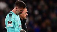 Kiper Juventus, Wojciech Szczesny berjalan meninggalkan lapangan dibantu oleh tim medis setelah mengalami sakit dada ketika pertandingan leg pertama perempat final Liga Europa 2022/2023 melawan Sporting CP di Allianz Stadium, Turin, Jumat (14/04/2023). Szczesny diketahui terkena paltisipasi jantung atau kondisi di mana seseorang merasakan kerja jantung yang kuat, cepat, atau tidak teratur. (AFP/Marco Bertorello)