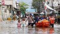 Personel kepolisian mengawal pemberian bantuan makanan siap saji kepada warga terdampak banjir rob di pemukiman padat penduduk Muara Angke, Jakarta Utara, Minggu (15/12/2024). (Liputan6.com/Herman Zakharia)