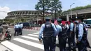 Polisi berkumpul untuk mengatur kerumunan di luar Stadion Olimpiade sebelum pertunjukan tim aerobatik Angkatan Udara Bela Diri Jepang (JASDF) Blue Impulse jelang upacara pembukaan Olimpiade Tokyo 2020 di Tokyo, Jepang, Jumat (23/7/2021). (Behrouz MEHRI/AFP)