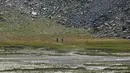 Pendaki berjalan di atas hamparan kering danau buatan Gabiet dekat Gressoney-La-Trinite di Lembah Aosta, Italia utara, Selasa (19/7/2022). Kekeringan parah masih melanda bagian utara negara itu. (AP Photo/Luca Bruno)