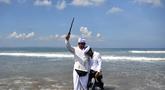 Seorang pria memegang keris saat sembahyang upacara Melasti di pantai Petitenget dekat Denpasar, di pulau resor Bali, Indonesia pada 19 Maret 2023. (AFP/SONNY TUMBELAKA)
