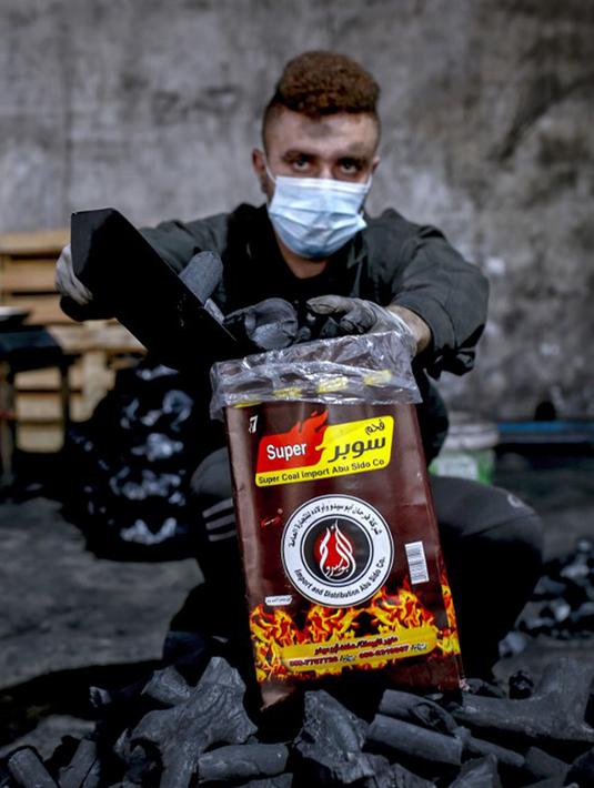 Seorang pekerja mengisi kantong arang di fasilitas produksi arang al-Hattab, sebelah timur Kota Gaza, Palestina, 28 Januari 2021. Fasilitas tersebut menghasilkan 80 hingga 90 ton arang per tahun. (Mohammed ABED/AFP)
