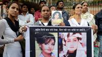 Fans aktris Bollywood Sridevi Kapoor memegang poster sang mendiang saat berdiri di luar rumah jelang pemakamannya, Mumbai, India, Rabu (28/2). (AP Photo/Rafiq Maqbool)